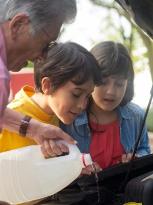 Dad showing kids how to pour coolant in car